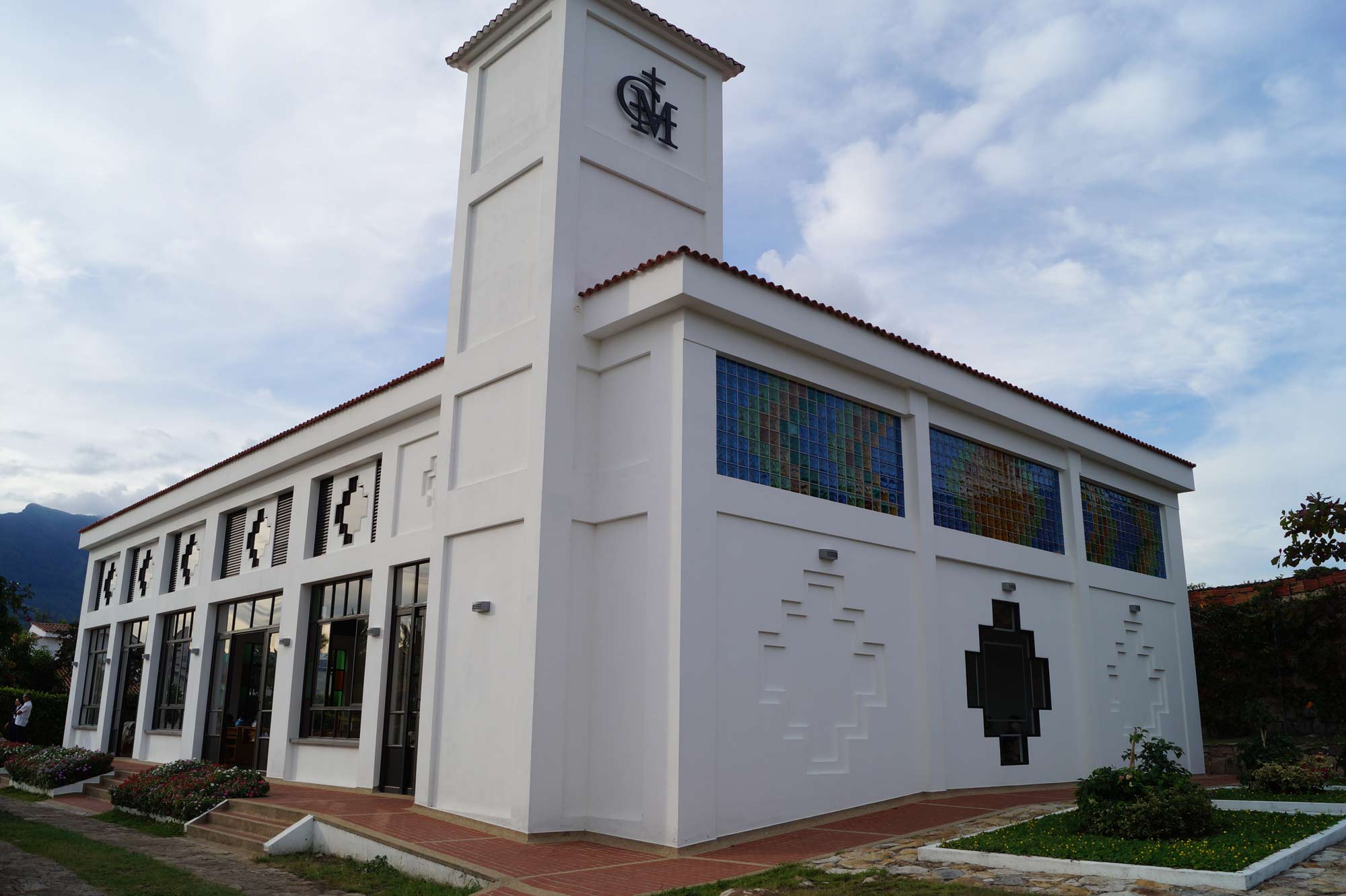 Arquitectura de la Capilla Cristo Evangelizador con torre, vitrales y jardines