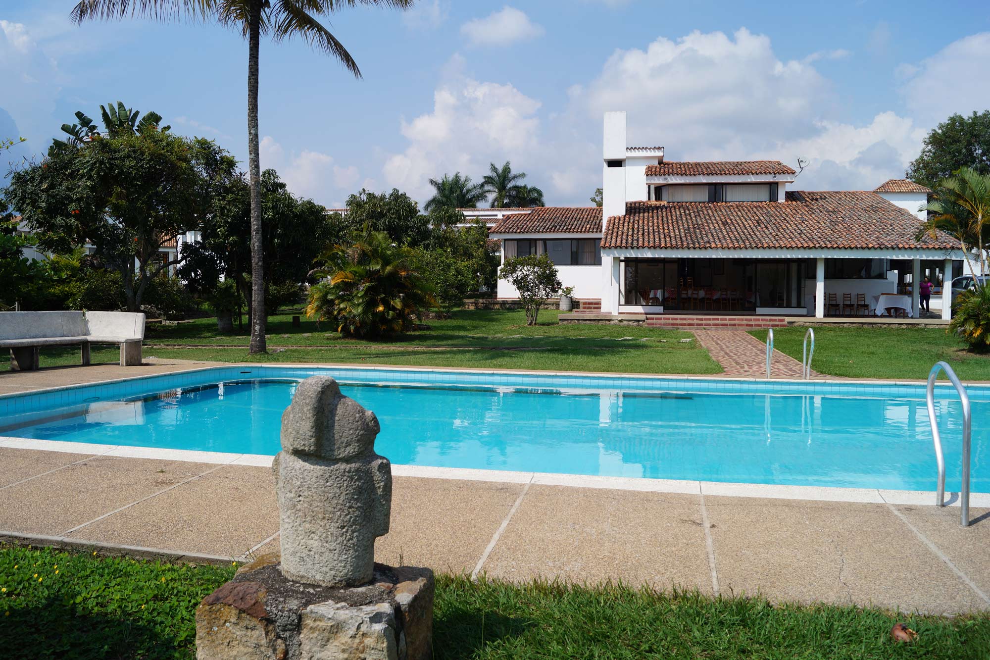 Piscina, jardines y edificio de la Casa Buenos Aires bajo un cielo azul