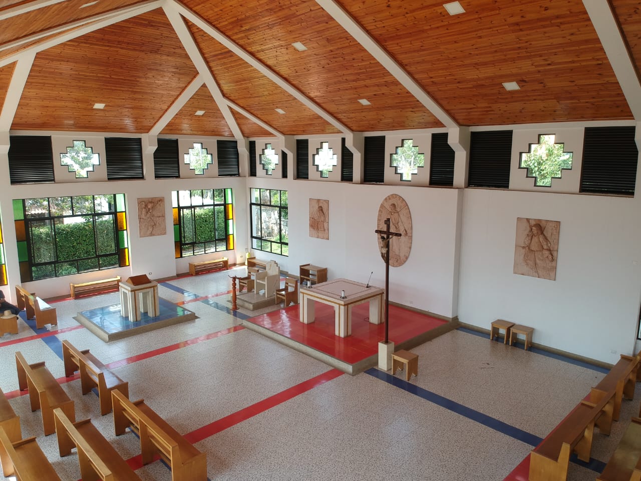 Interior de la capilla Cristo Evangelizador, con altar, crucifijo y bancas bajo una cubierta de madera